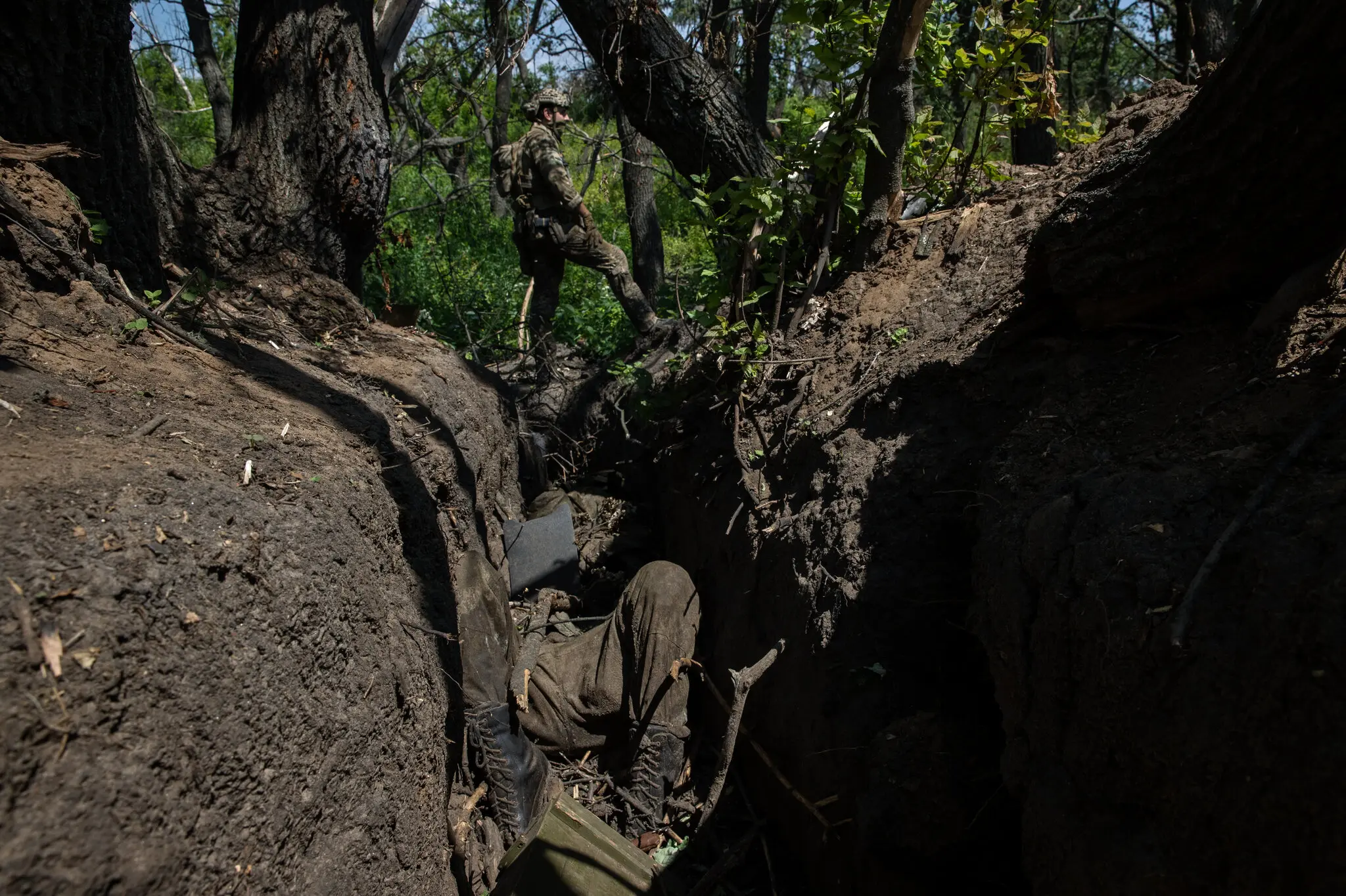 Солдат 3-ї окремої десантно-штурмової бригади ЗСУ біля трупа російського військовослужбовця в окопі на передовій на південь від міста Бахмут, 9 червня.